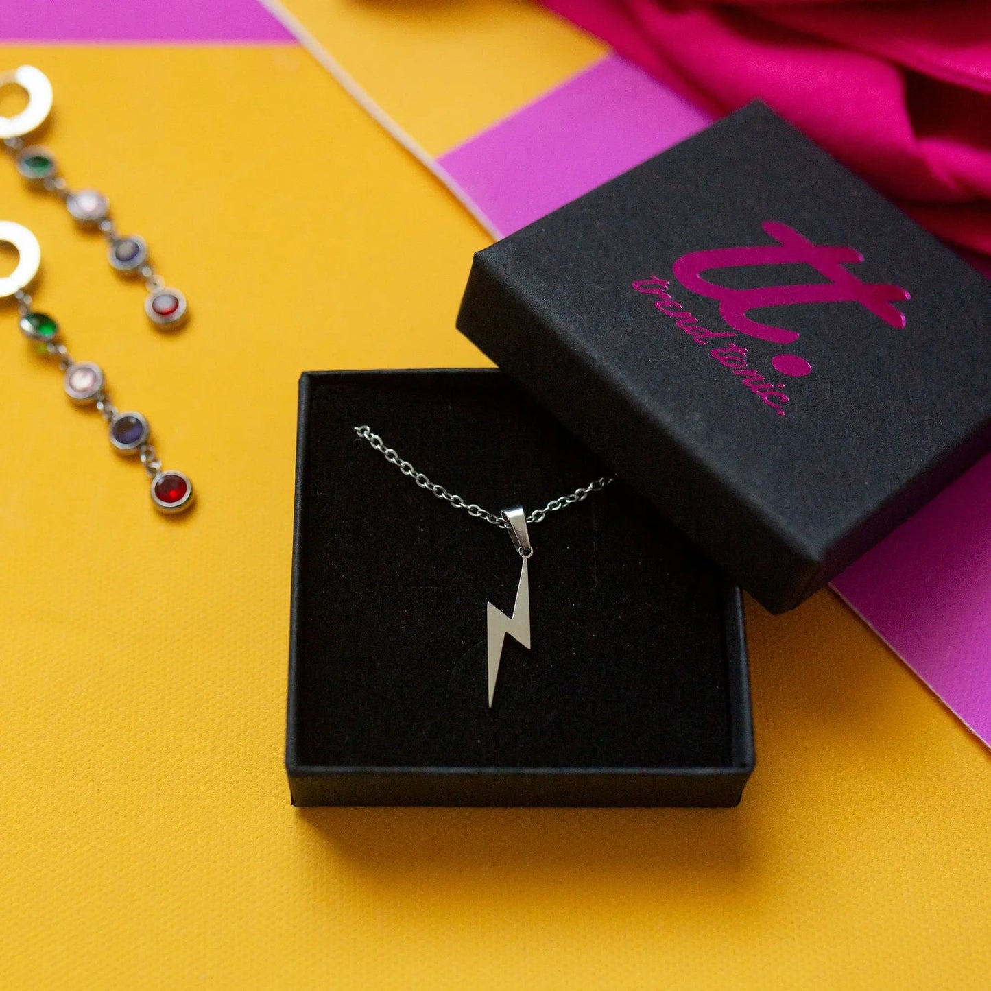 Silver lightning bolt necklace in a black box on a colorful background