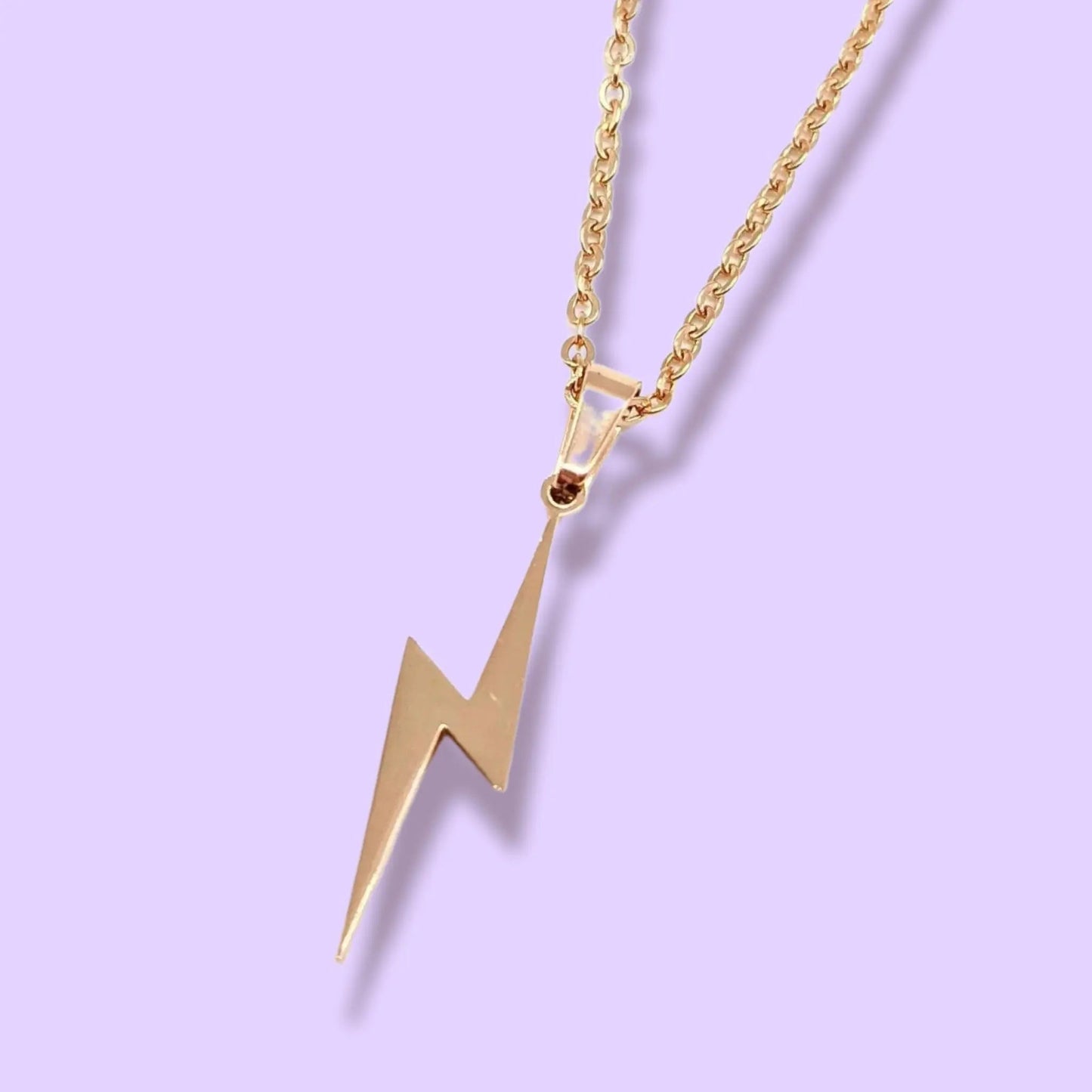 Gold lightning bolt pendant necklace on a light purple background
