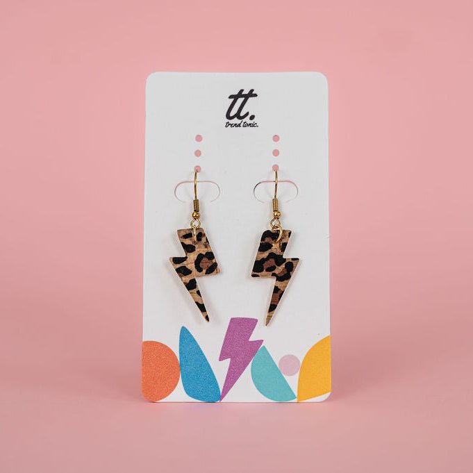 Leopard print lightning bolt earrings on a branded card with a pink background