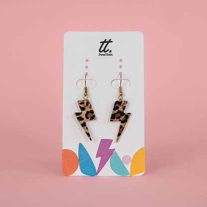 Leopard print lightning bolt earrings on a branded card with a pink background