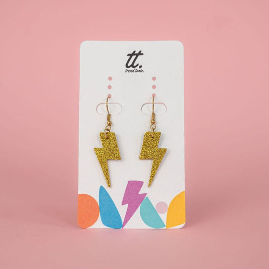 Gold glitter lightning bolt earrings on a branded card with a pink background
