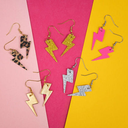 Collection of colorful lightning-shaped earrings on a pink and yellow background