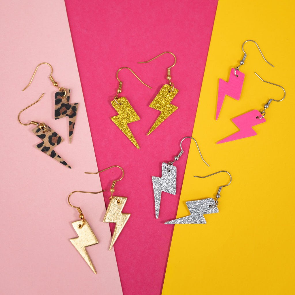 Collection of colorful lightning-shaped earrings on a pink and yellow background
