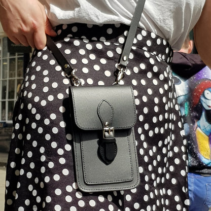 Person wearing a black and white polka dot skirt with a gray crossbody bag.