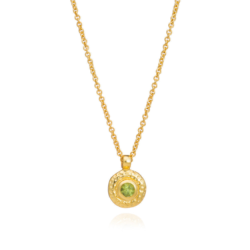 Gold necklace with a green gemstone pendant on a white background