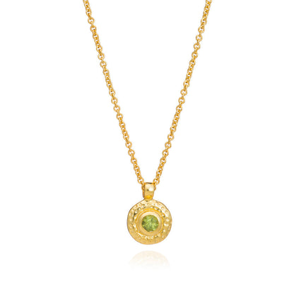 Gold necklace with a green gemstone pendant on a white background