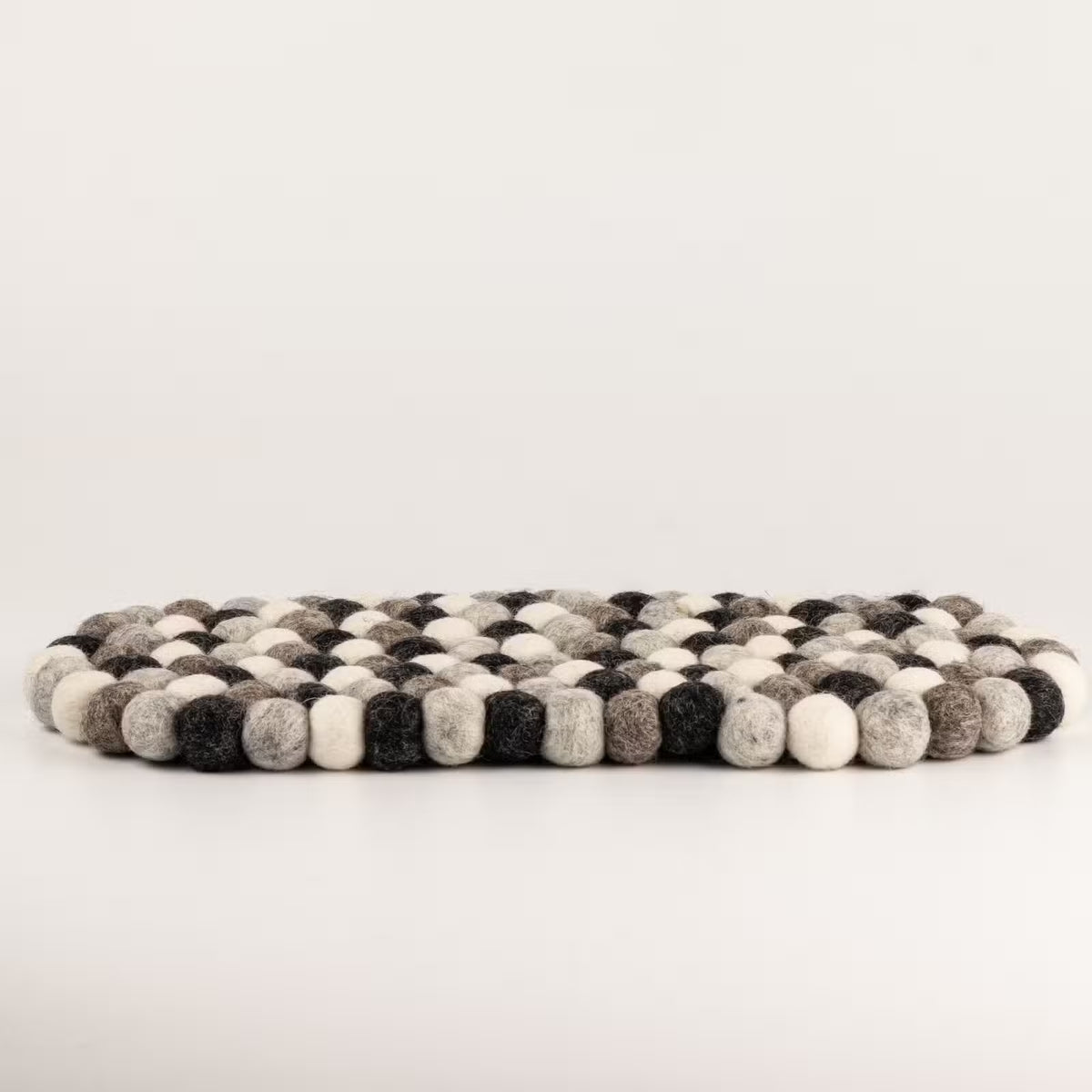 Side view of the grey felt ball oval mat showing its thickness