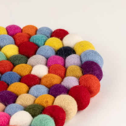 Close-up of the edge of the multicolour felt ball oval mat, showing pink, yellow, blue, red and purple wool balls