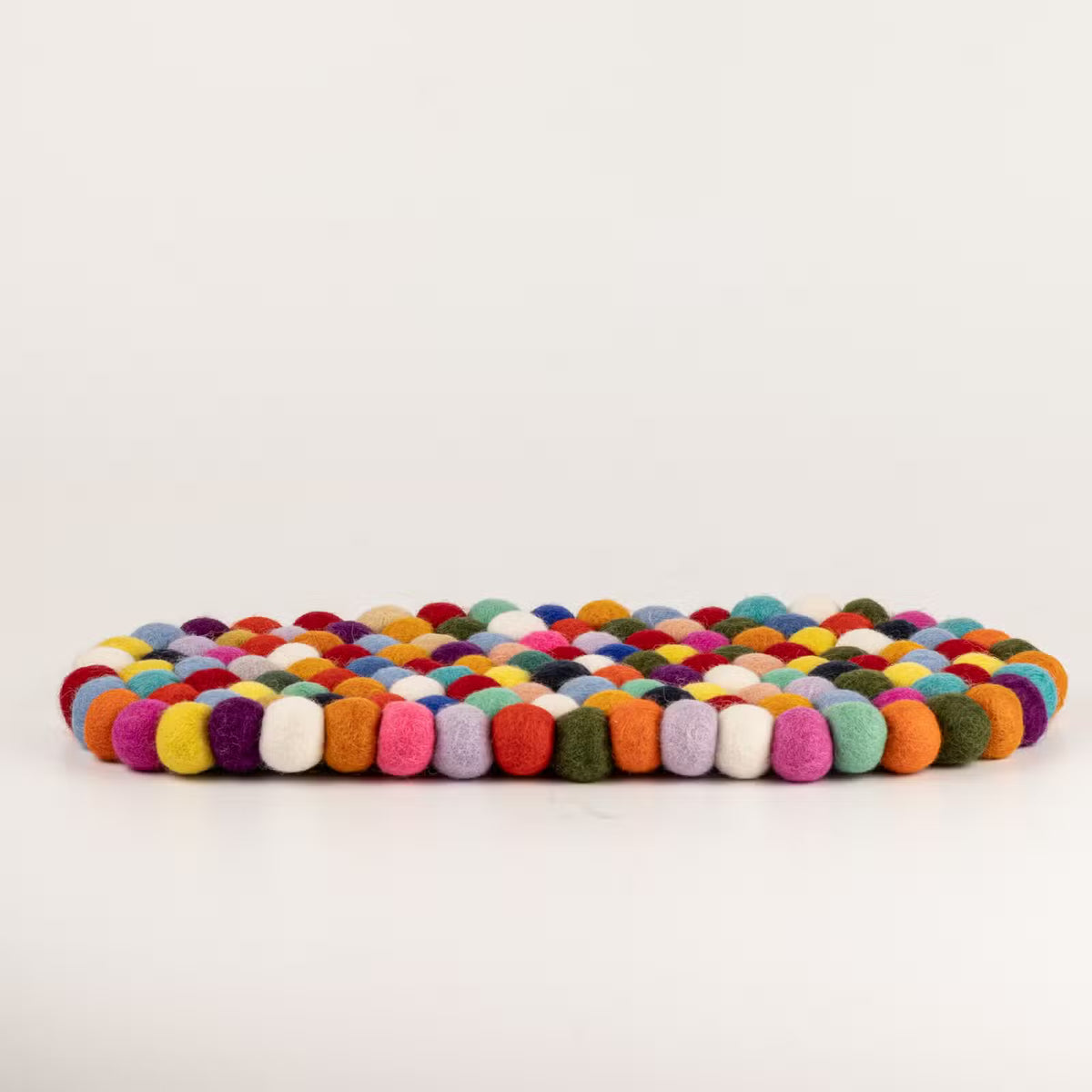 Side view of the multicolour felt ball oval mat showing its thickness