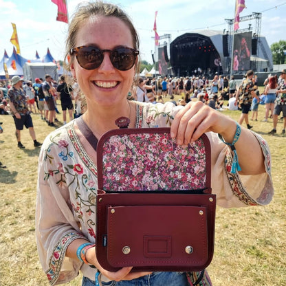 Woman holding a floral-patterned handbag at a music festival.