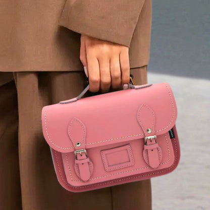 Pink handbag held by a person wearing a beige coat.
