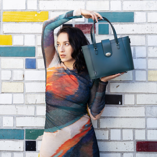 Woman holding a green handbag against a colorful brick wall.