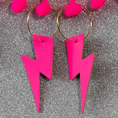 Pink lightning bolt earrings on a glittery gray background