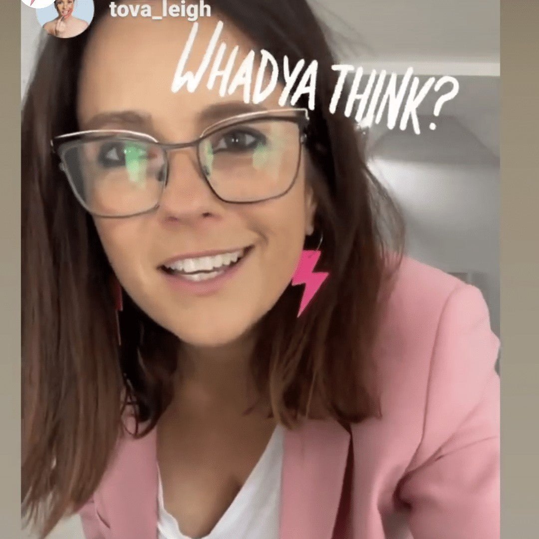 Person wearing glasses and a pink blazer with text 'WHADYA THINK?'