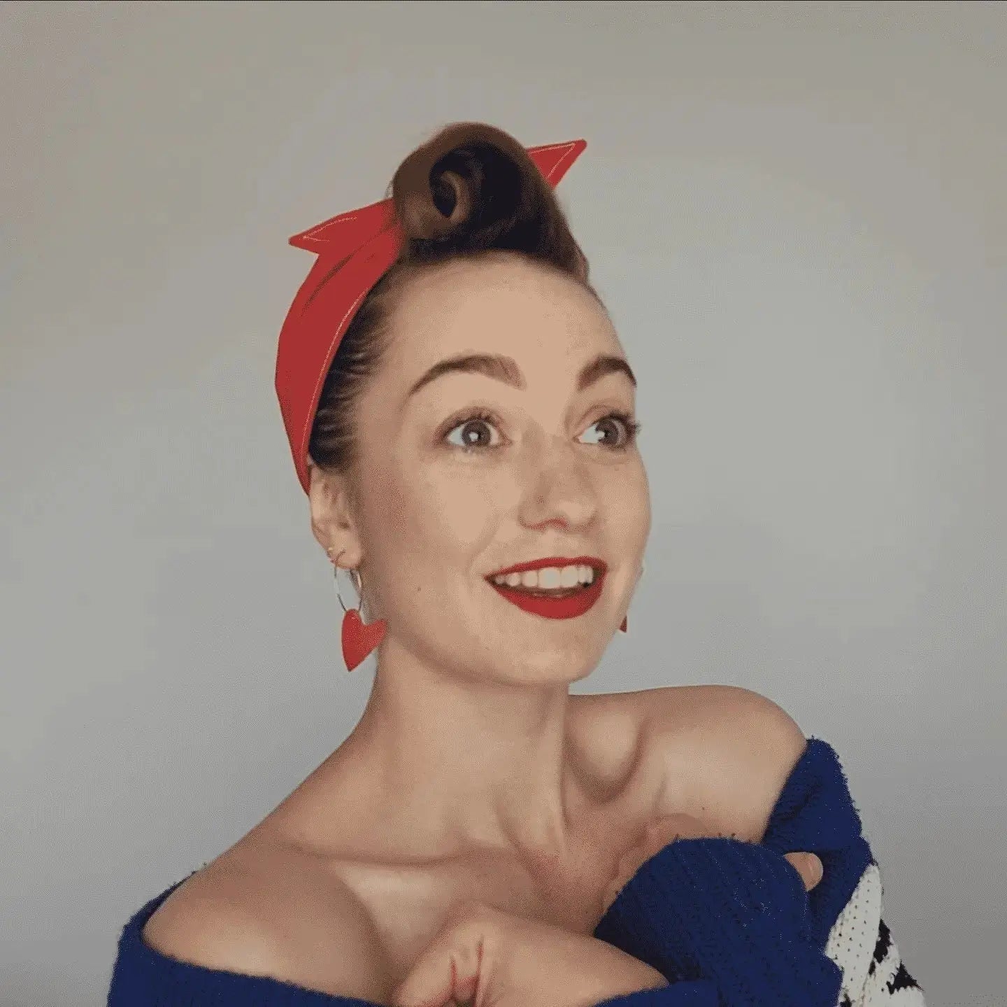Woman wearing a red headband with a star design on a plain background