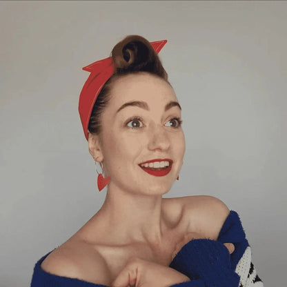 Woman wearing a red headband with a star design on a plain background