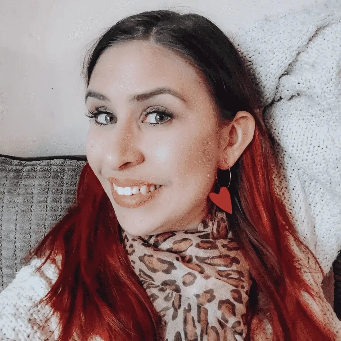 Woman with red hair wearing a leopard print scarf, smiling at the camera.