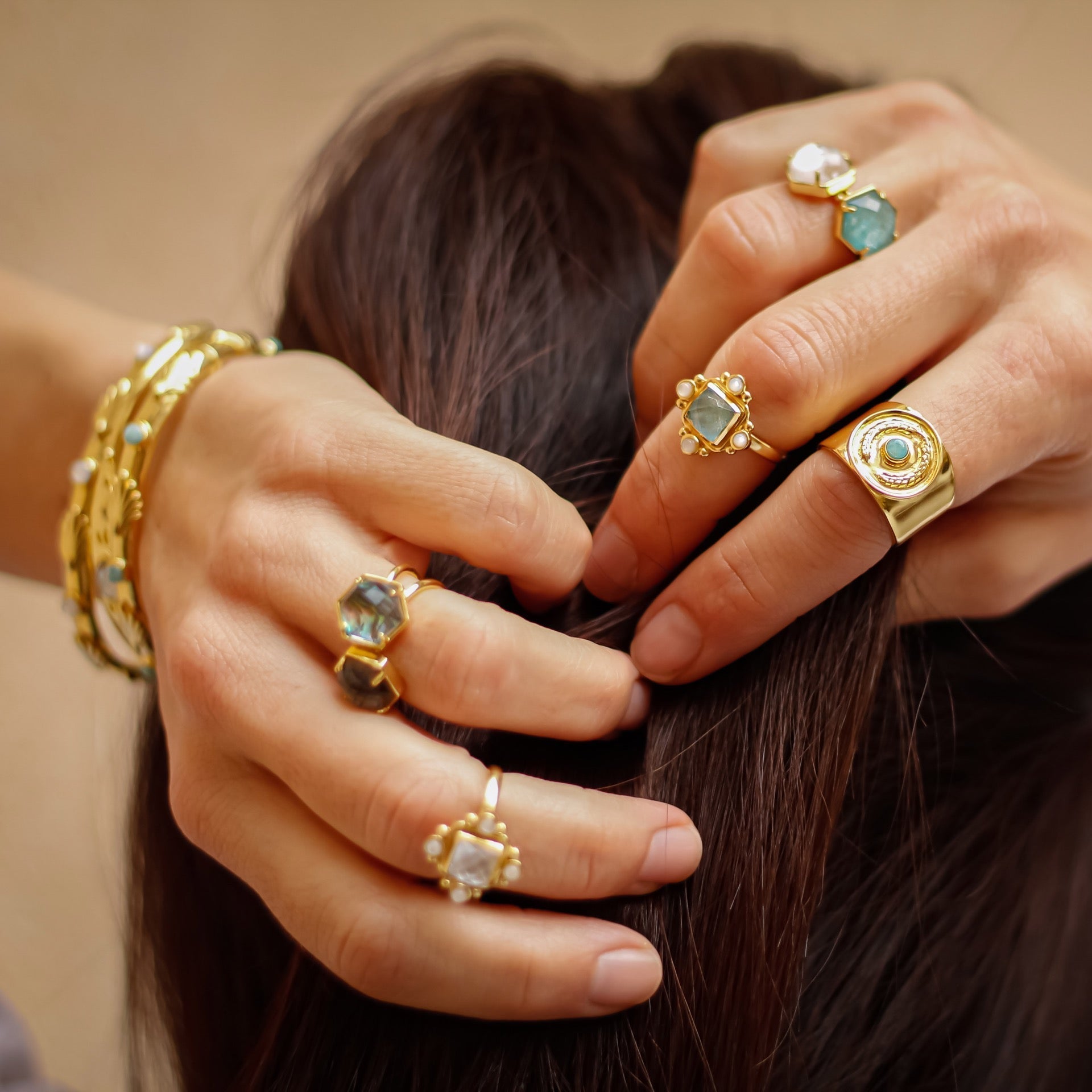 Close-up of hands with gold rings and bracelets on a blurred background