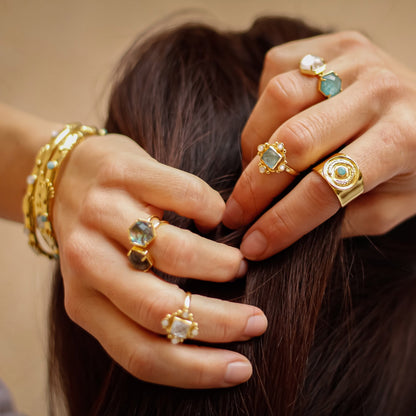 Close-up of hands with gold rings and bracelets on a blurred background