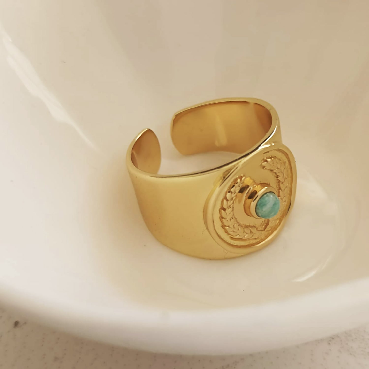 Gold ring with a turquoise stone on a white dish