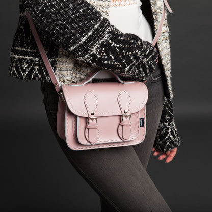 Person wearing a pink satchel bag with a dark background