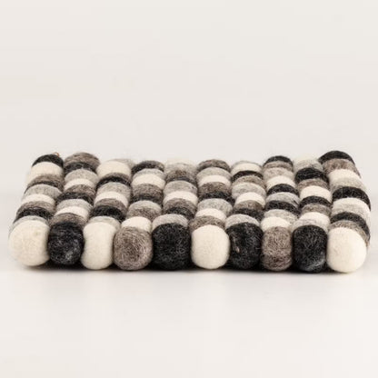 Side view of the grey felt ball square placemat showing its 2cm thickness