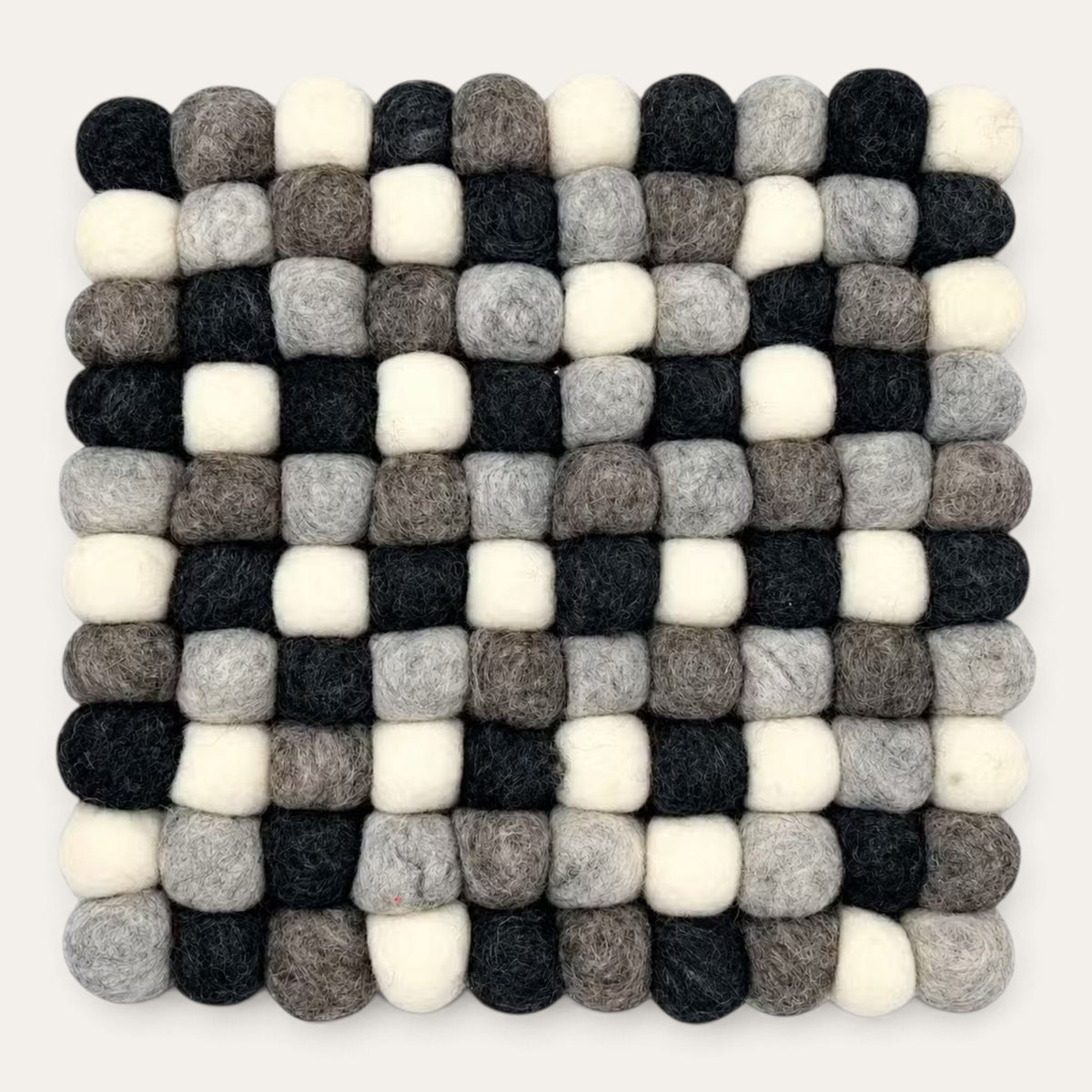 Grey felt ball square placemat seen from above in charcoal, grey, taupe and cream wool balls