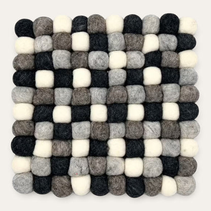 Grey felt ball square placemat seen from above in charcoal, grey, taupe and cream wool balls