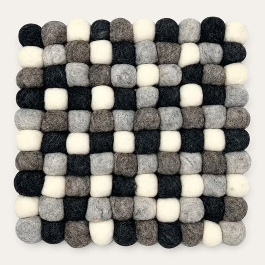 Grey felt ball square placemat seen from above in charcoal, grey, taupe and cream wool balls