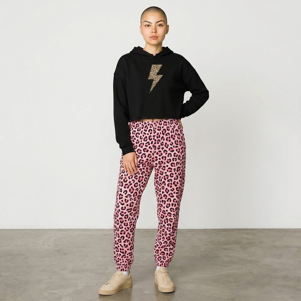 Person wearing a black hoodie with a leopard print design and pink leopard print pants on a plain background